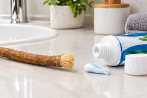 Miswak stick beside a tube of toothpaste on a bathroom counter