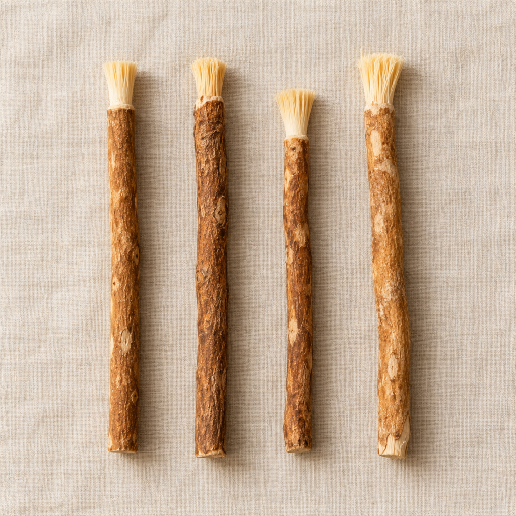 Four miswak sticks laid in a row on linen fabric