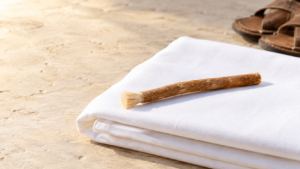 Miswak stick resting on folded white ihram cloth with sandals nearby