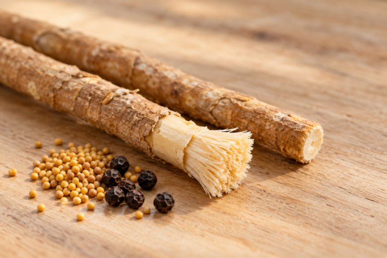 Fresh miswak sticks with frayed tips beside mustard seeds and peppercorns