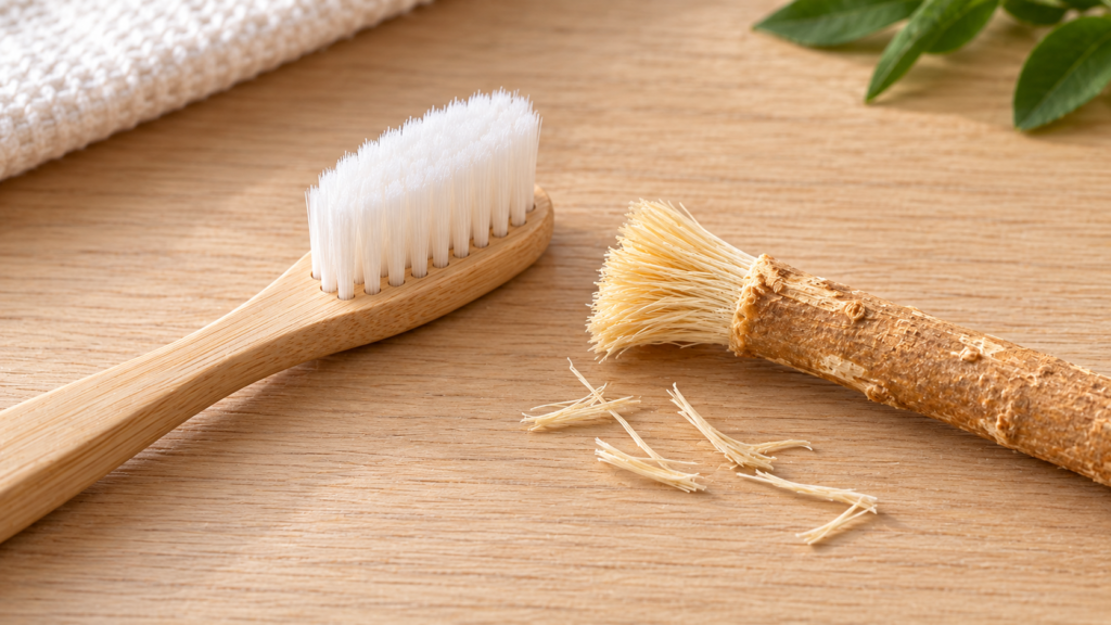 Soft toothbrush beside a miswak stick with a few loose fibres